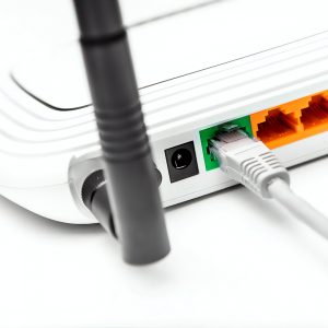 Network cable connected to wifi router on white background.