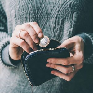 Hands holding british pound coin and small money pouch by 123rf