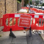 Works to lay new paving slabs and temporary footpath closed red warning sign on London sidewalk by 123rf
