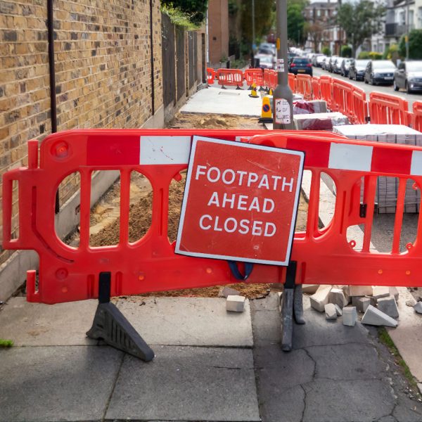 Works to lay new paving slabs and temporary footpath closed red warning sign on London sidewalk