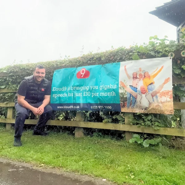 Kloud9-worker-next-to-banner-on-rural-road