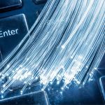 Bundle of optical fibers with lights in the ends lay on keyboard.