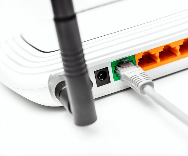 Network cable connected to wifi router on white background.